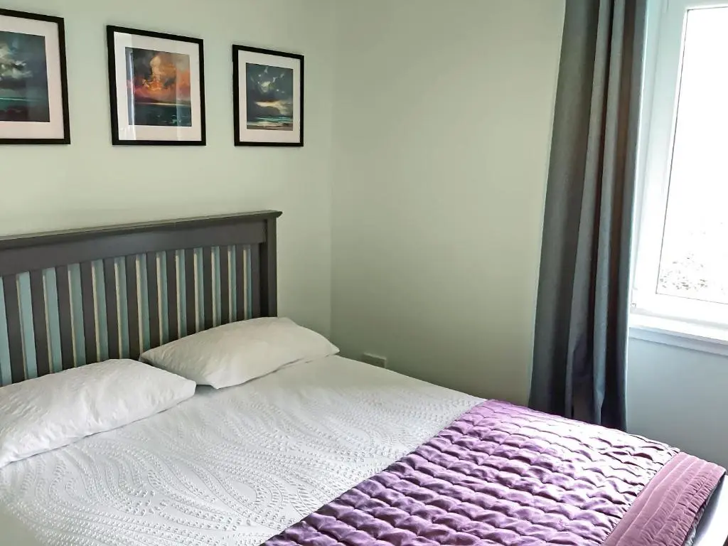a bedroom with a bed with a purple blanket at Seasgair in Dingwall