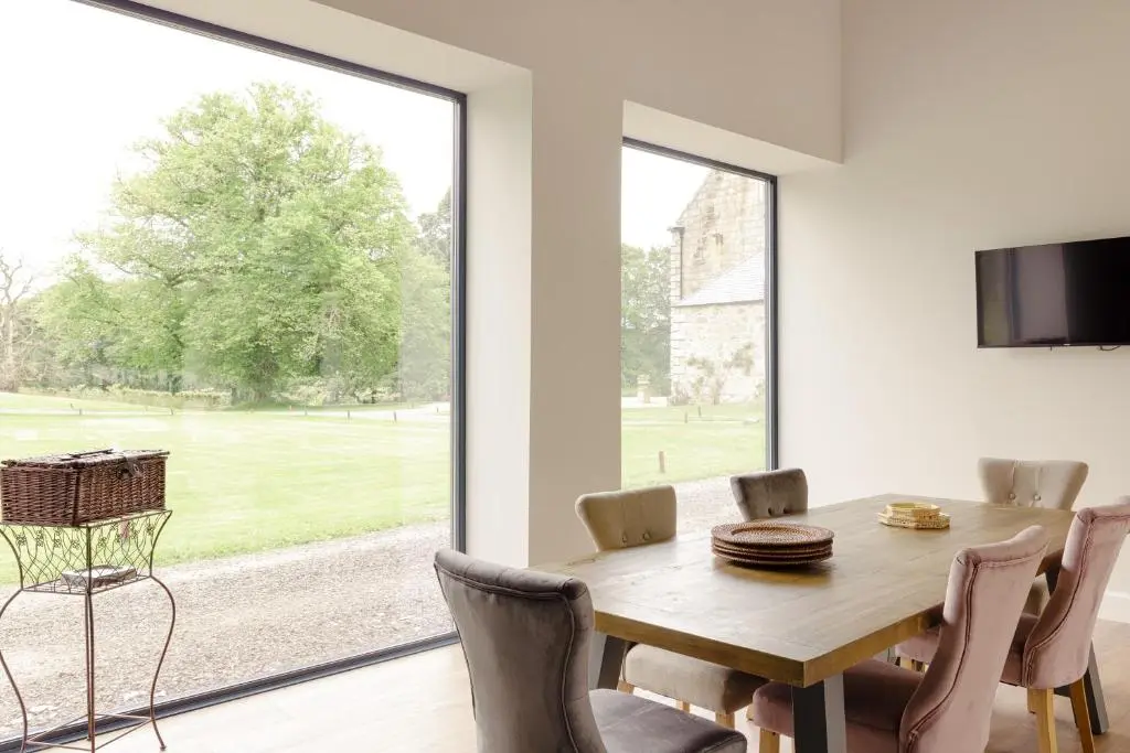a dining room with a table and a large window at Elrick Estate - Coach House in Newmachar