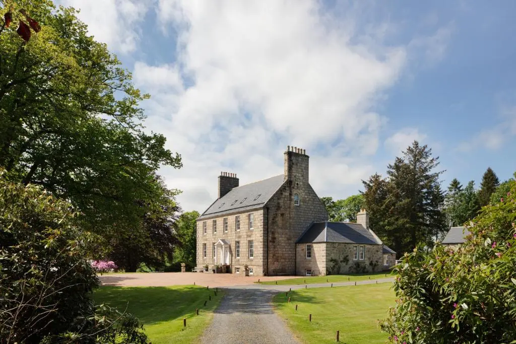 a large brick building on a green field at Elrick Estate - Coach House in Newmachar