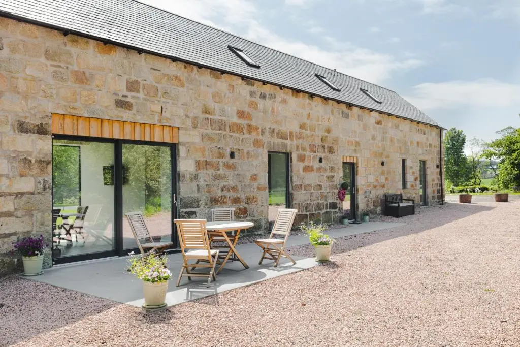 a brick building with a table and chairs on a patio at Elrick Estate - Coach House in Newmachar