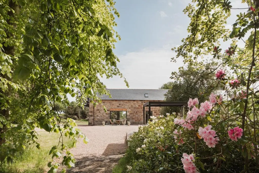 a brick house with a courtyard and flowers at Elrick Estate - Coach House in Newmachar