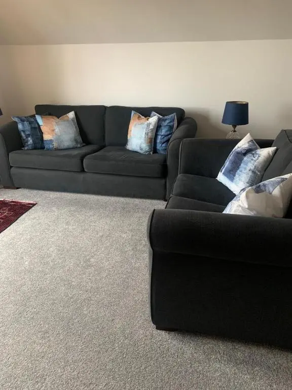 a living room with a black couch with pillows at Inchmarlo Villa 29 Banchory in Inchmarlo