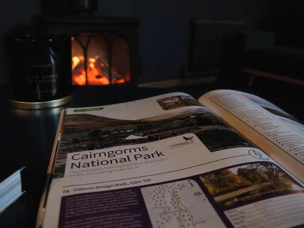 a book sitting on top of a table with a fireplace at Old Manse of Craggan in Glenlivet