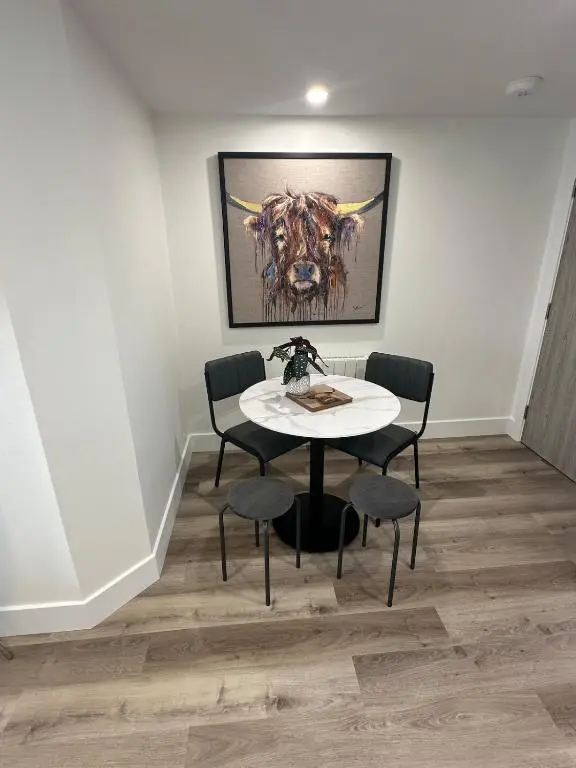 a table and chairs in a room with a painting at St\u0101 by The Bridge, Inverness City Centre in Inverness