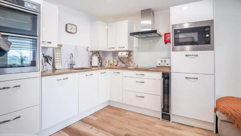 a white kitchen with white cabinets and appliances at St\u0101 by The Bridge, Inverness City Centre in Inverness