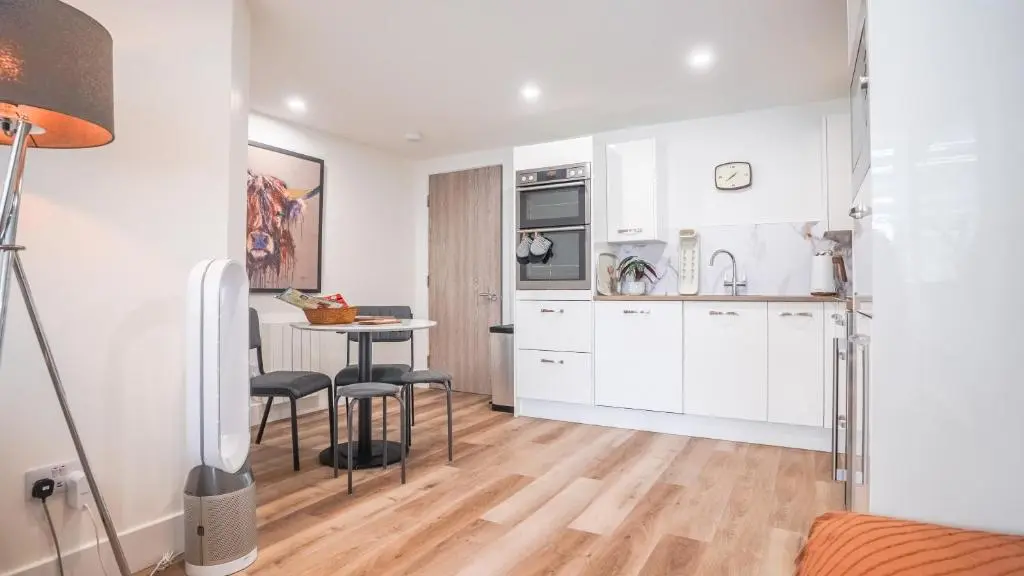 a kitchen with white cabinets and a table and chairs at St\u0101 by The Bridge, Inverness City Centre in Inverness