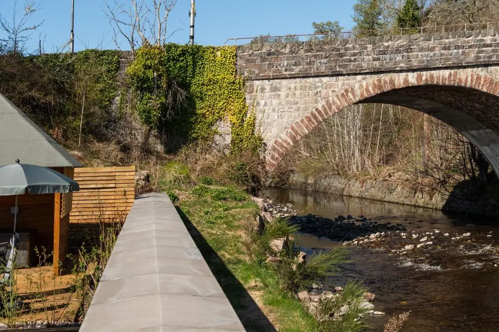 a brick bridge over a river with a path at Bridgend Bothy in Drumnadrochit