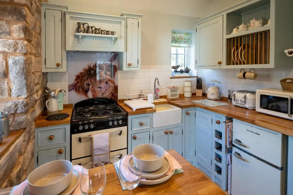 a kitchen with blue cabinets and a stove top oven at Bridgend Bothy in Drumnadrochit