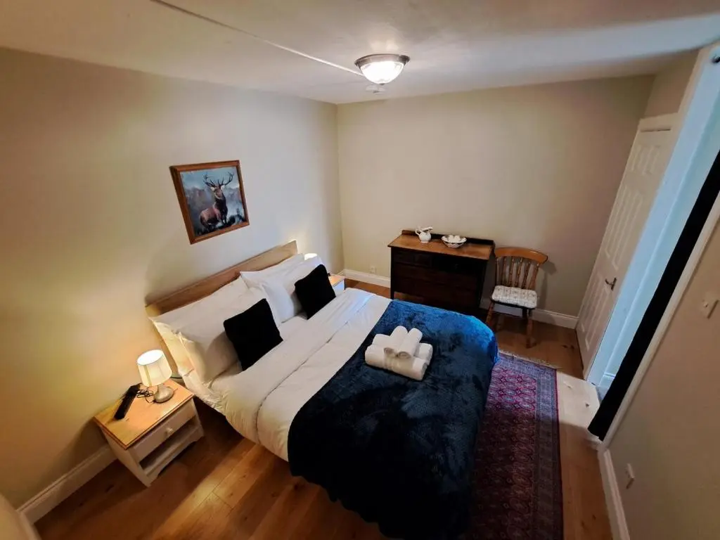 a bedroom with a large bed with a blue blanket at Cosy Riverside Apartment with free parking in Inverness