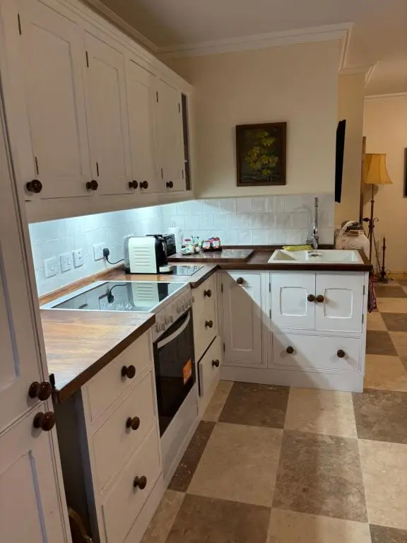 a kitchen with white cabinets and a tile floor at Garden Cottage in Cambus O\u02bcMay Station