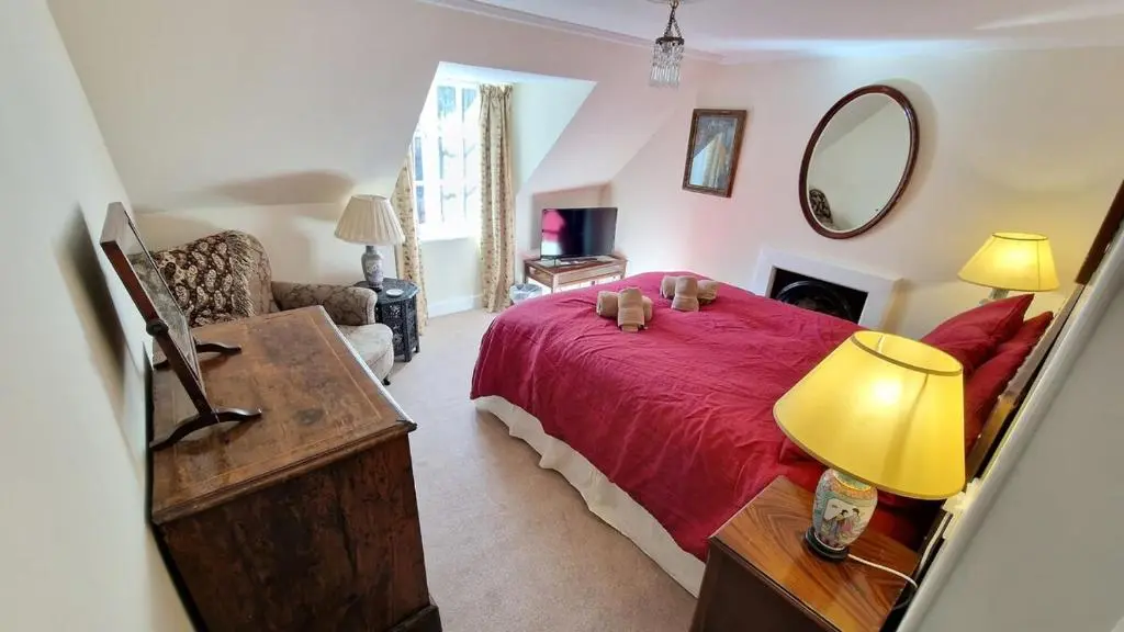 a bedroom with a red bed and a mirror at Garden Cottage in Cambus O\u02bcMay Station