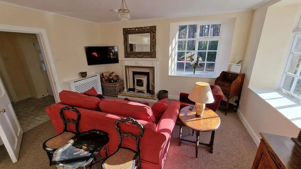 a living room with a red couch and a fireplace at Garden Cottage in Cambus O\u02bcMay Station