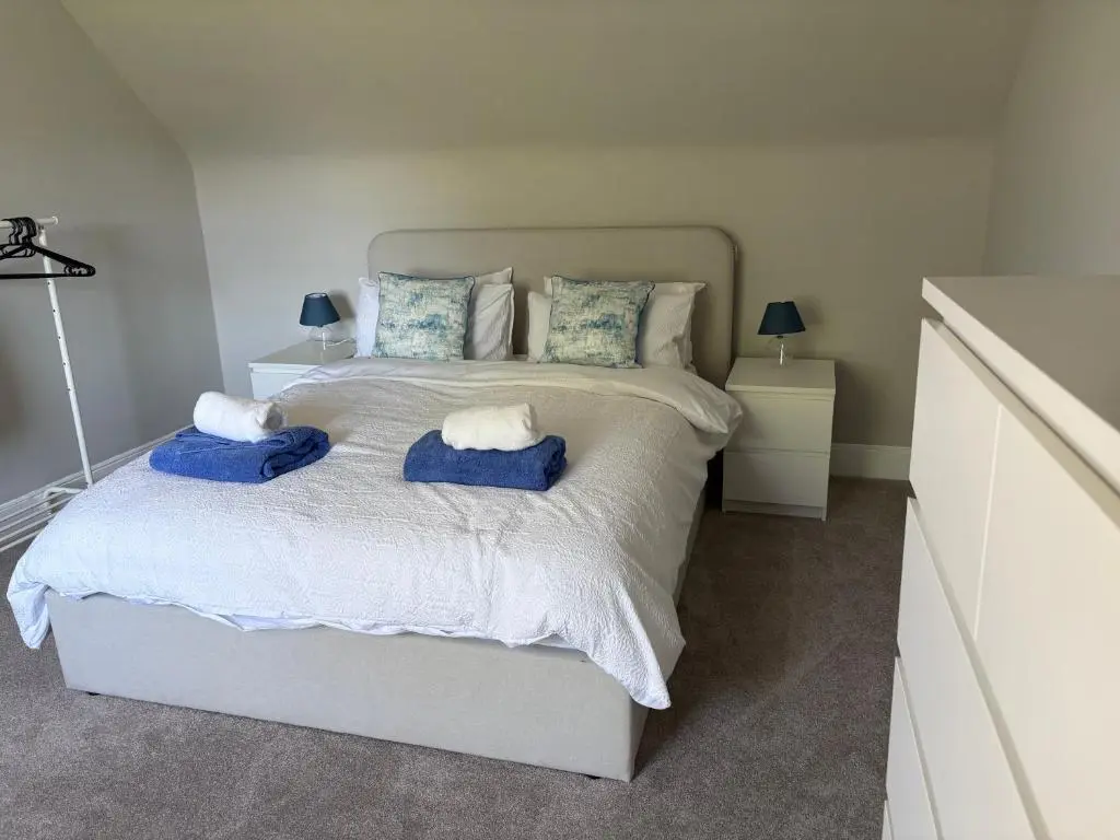a bedroom with a bed with blue towels on it at 2 Links Place in Nairn