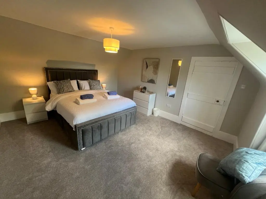 a bedroom with a large bed and a chair at 2 Links Place in Nairn