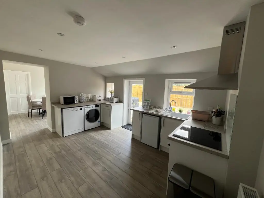 a large kitchen with white appliances and wooden floors at 2 Links Place in Nairn