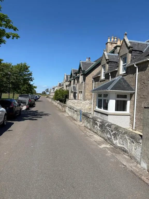 an empty street with houses and cars parked on the side at 2 Links Place in Nairn