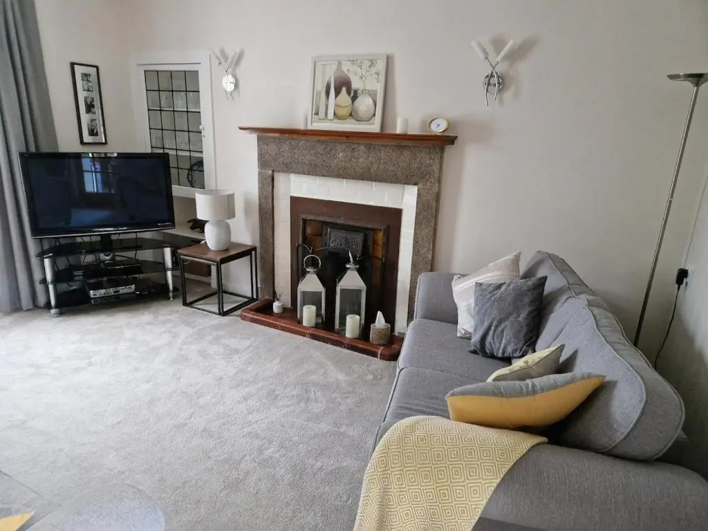 a living room with a couch and a fireplace at Spacious cosy welcoming cottage in Ballater