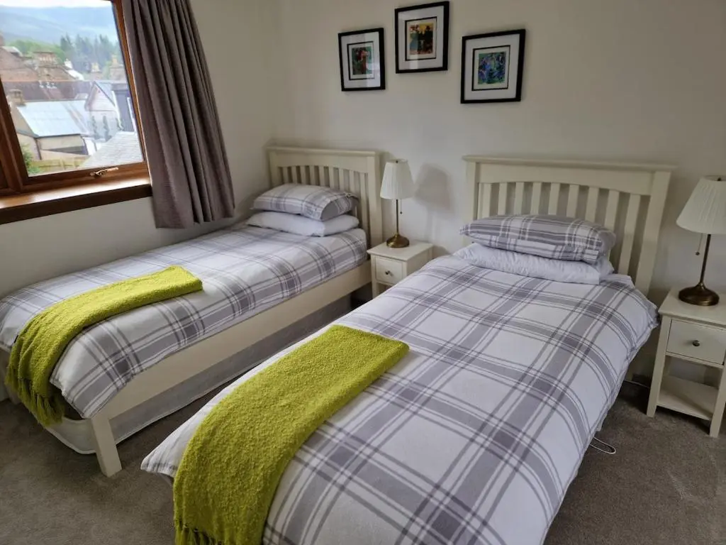 two beds sitting next to each other in a bedroom at Spacious cosy welcoming cottage in Ballater