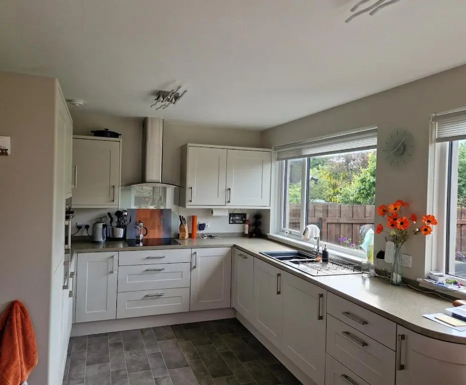 a kitchen with white cabinets and a window at Spacious cosy welcoming cottage in Ballater