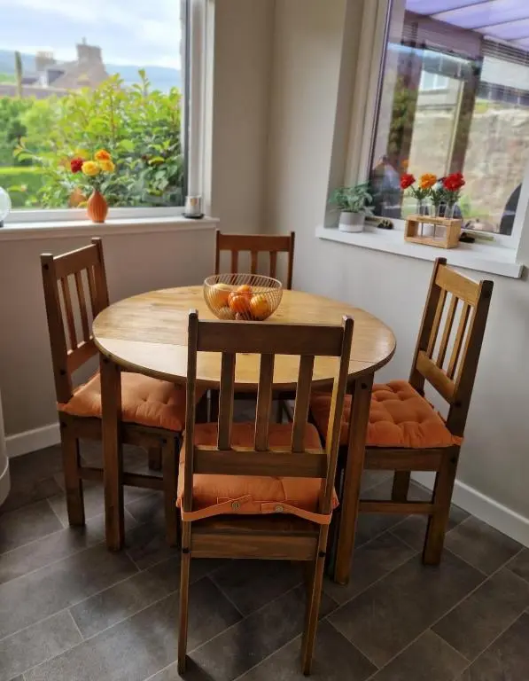 a wooden table with chairs and a bowl of fruit on it at Spacious cosy welcoming cottage in Ballater