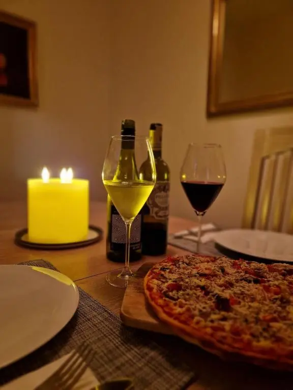 a table with a pizza and two glasses of wine at Spacious cosy welcoming cottage in Ballater