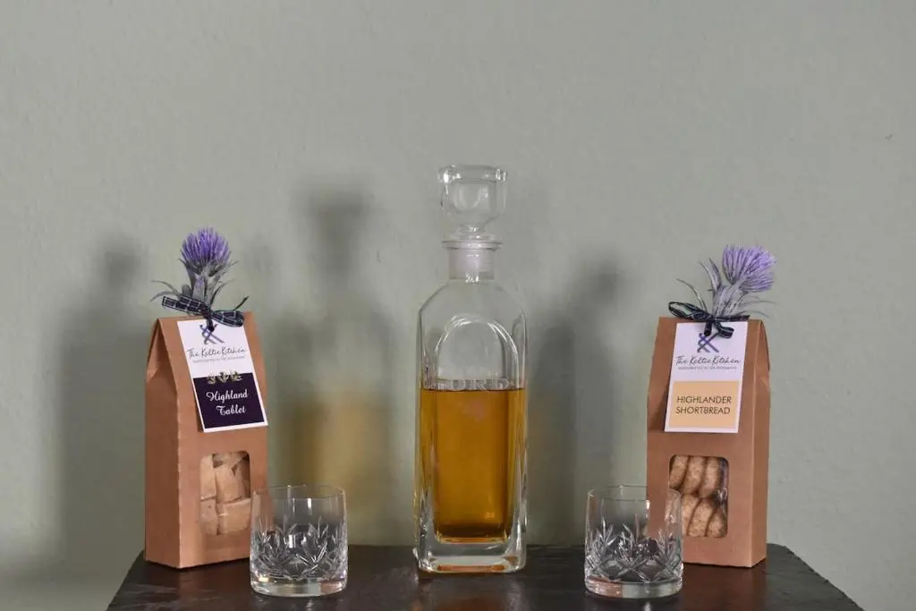 a bottle of alcohol sitting on a table with two glasses at The MacKenzie Apartment in Beauly