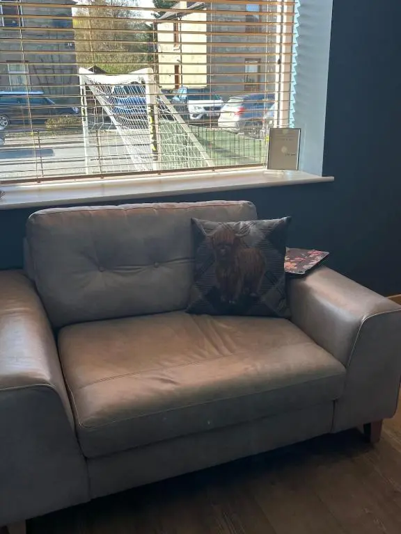 a brown leather couch in a room with a window at Charlies in Huntly