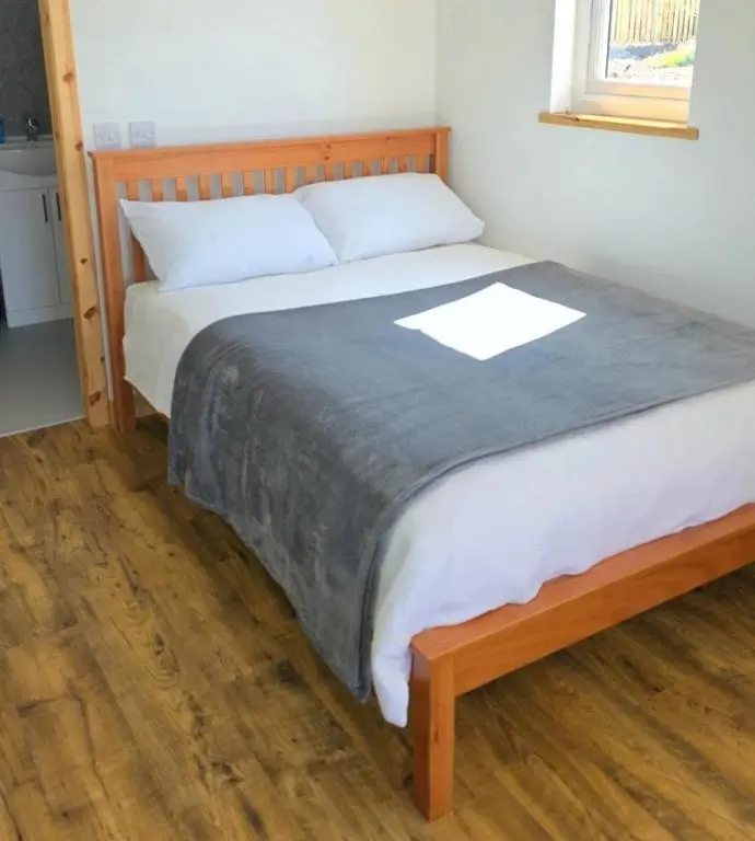 a bedroom with a large bed with a wooden headboard at Cabin View in Cuminestown