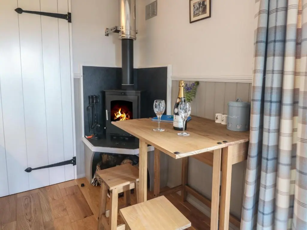 a kitchen with a table with a fireplace in a room at Coraldie in Newtonmore