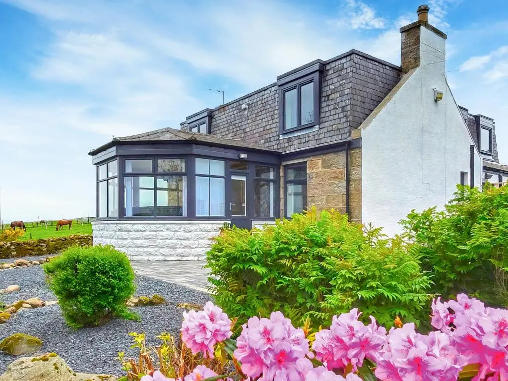 a brick house with black windows and pink flowers at Hogholm Farmhouse in Inverurie