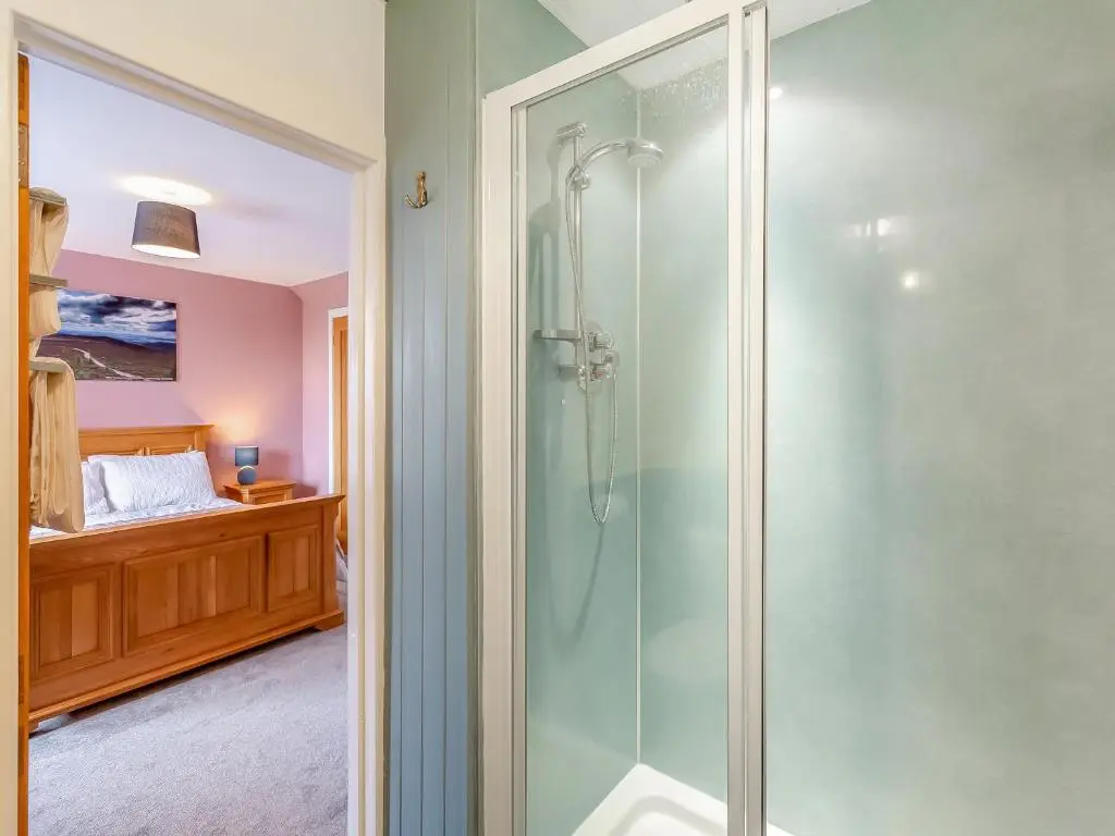 a glass shower in a bathroom with a bed at Hogholm Farmhouse in Inverurie