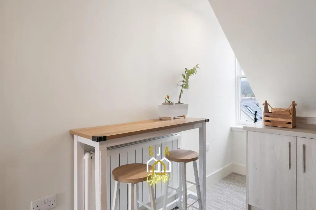 a kitchen with a table and two stools at Ballater Retreat - SJA Stays - Modern 1 Bed Apartment in Ballater