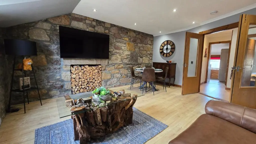 a living room with a stone fireplace with a tv at Stylish 1-Bed City Centre Flat in Inverness