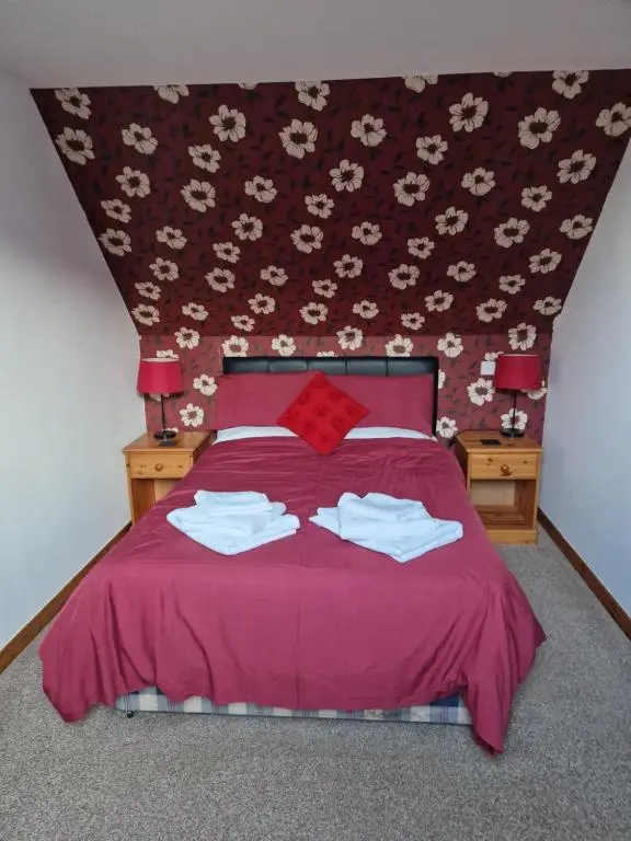 a bedroom with a pink bed with two towels on it at The harbour inn in Burghead
