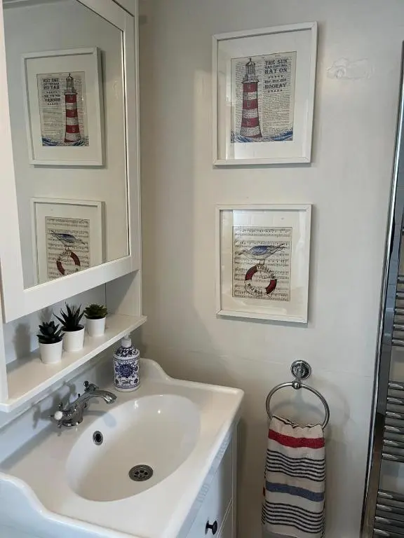 a bathroom with a sink and two pictures on the wall at Craigen Cottage Ballater in Ballater