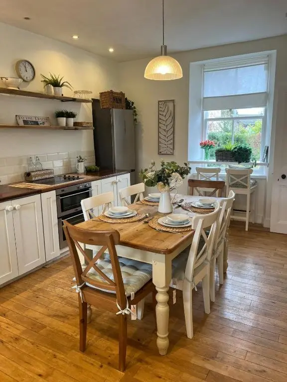 a kitchen and dining room with a wooden table and chairs at Craigen Cottage Ballater in Ballater