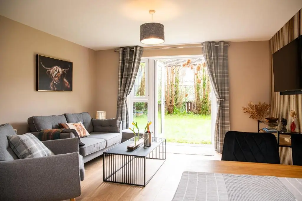 a living room with a couch and a table at Highland Cow Apartment in Inverness