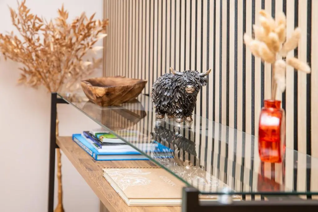 a glass table with a statue of a bull on it at Highland Cow Apartment in Inverness