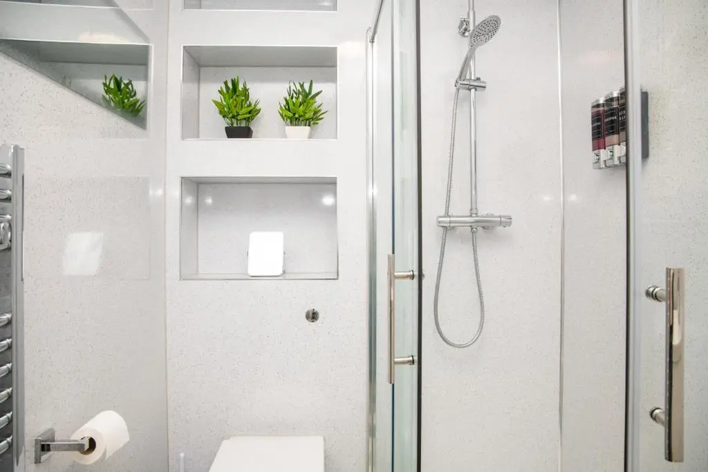 a bathroom with a shower with plants on shelves at Highland Cow Apartment in Inverness