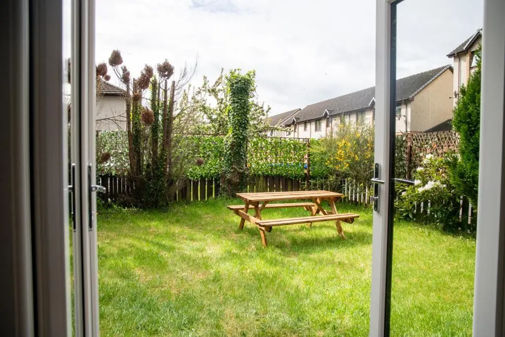 a window view of a picnic table in a yard at Highland Cow Apartment in Inverness