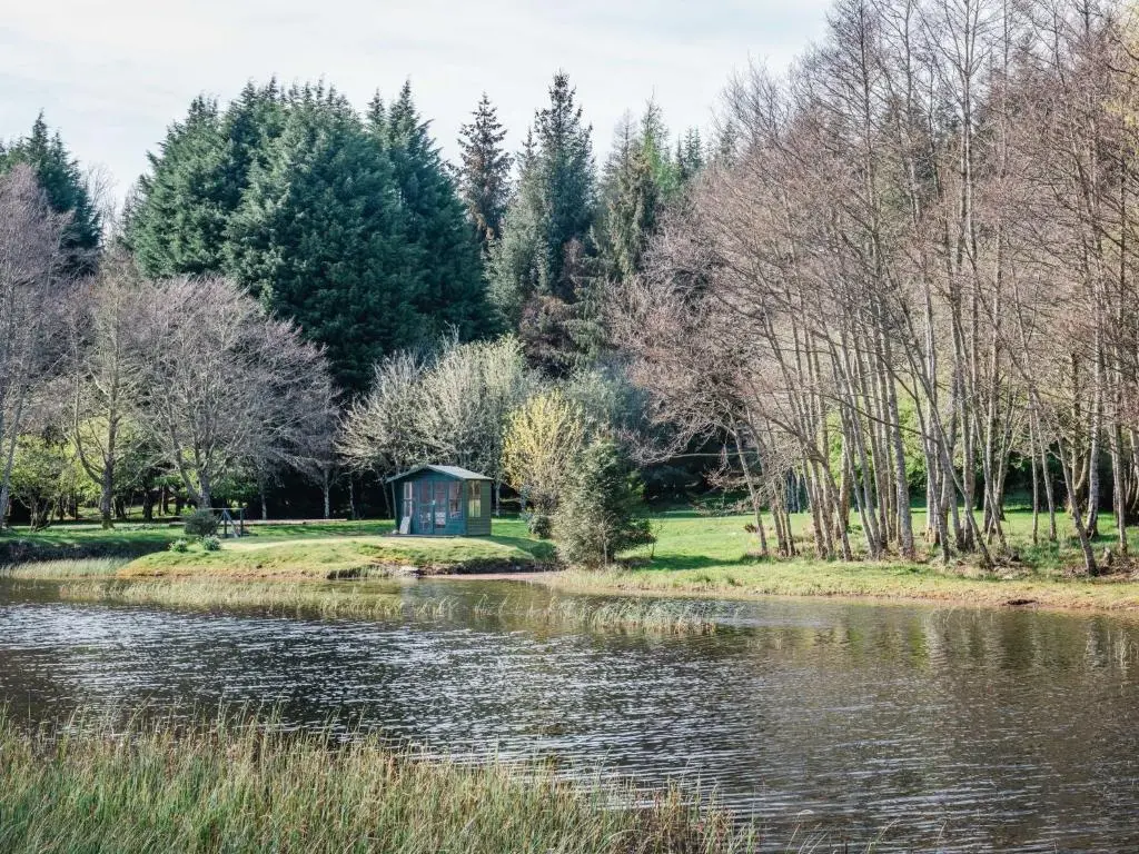 a small blue shack next to a river at Holiday Home Farmburn Bothy by Interhome in Invermoriston