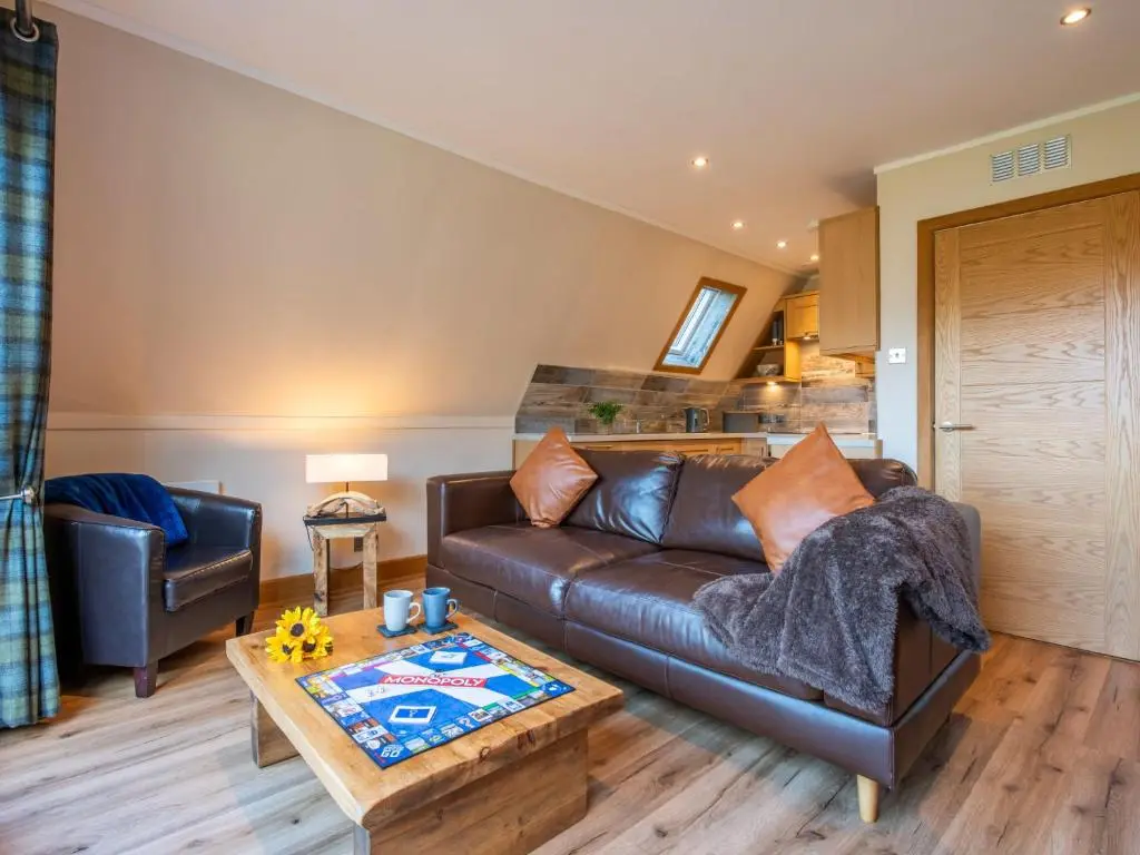 a living room with a leather couch and a table at Chalet Sandpiper Lodge by Interhome in Spean Bridge