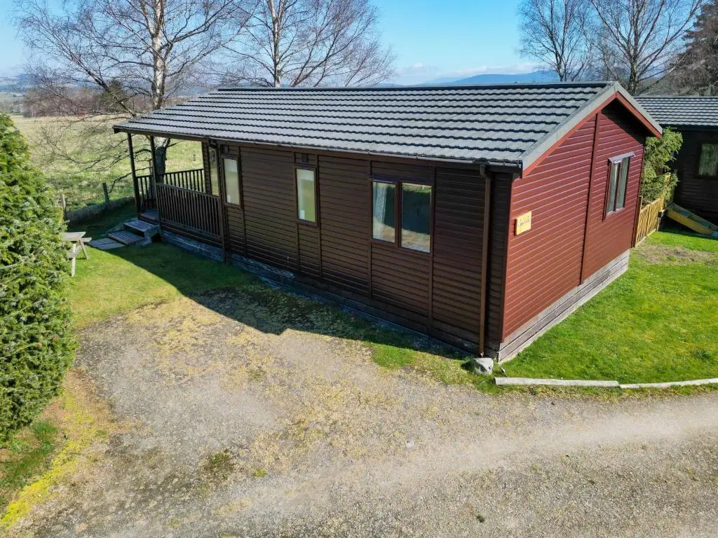 a red and black tiny house on a yard at Chalet Lodge 5 by Interhome in Boat of Garten