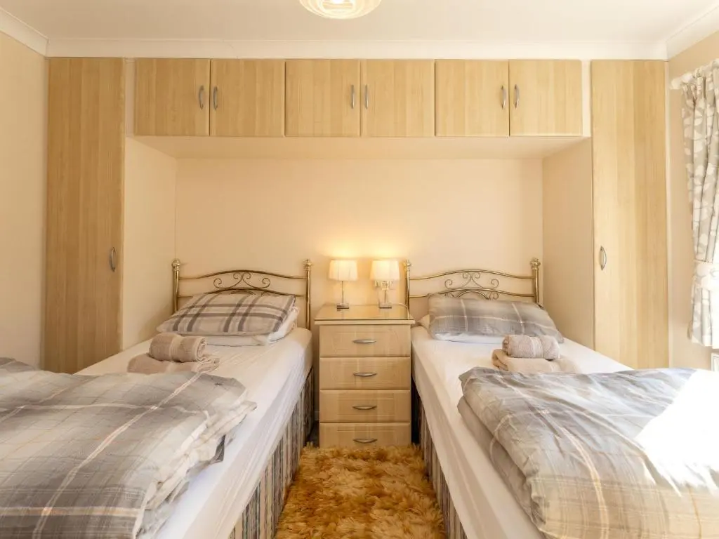 two twin beds in a bedroom with wooden cabinets at Chalet Lodge 5 by Interhome in Boat of Garten