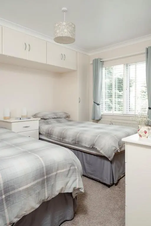 a white bedroom with two beds and a window at Chalet Lodge 7 by Interhome in Boat of Garten