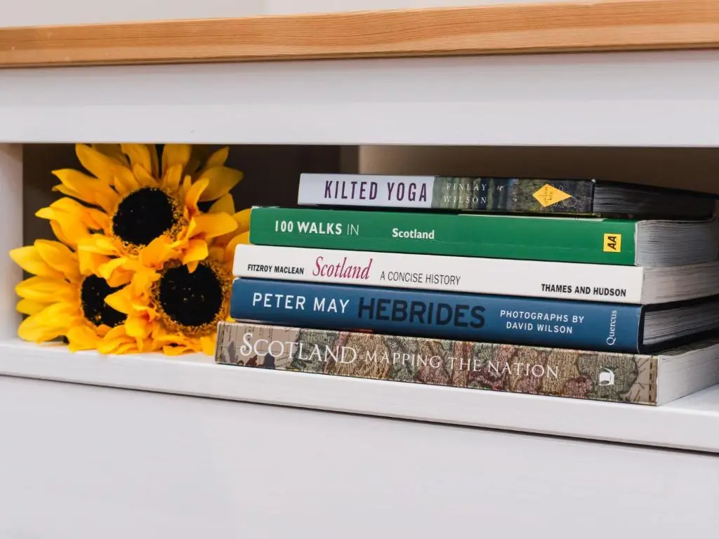 a stack of books on a shelf with sunflowers at Apartment Wayside Loft by Interhome in Drumnadrochit