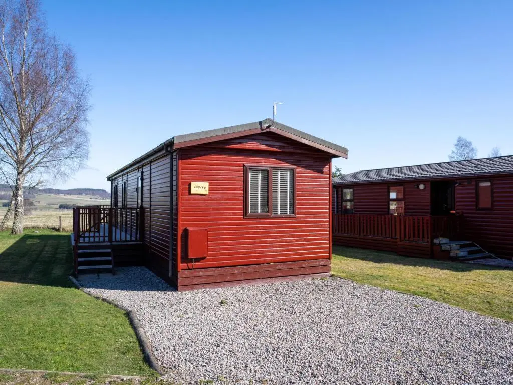 a red and black tiny house sitting on gravel at Chalet Lodge 3 by Interhome in Boat of Garten