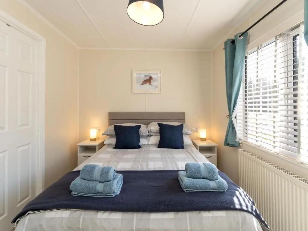 a bedroom with a large bed with blue pillows at Chalet Lodge 3 by Interhome in Boat of Garten