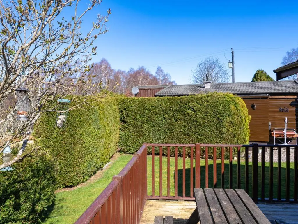a fence and a bench in front of a hedge at Chalet Lodge 4 by Interhome in Boat of Garten