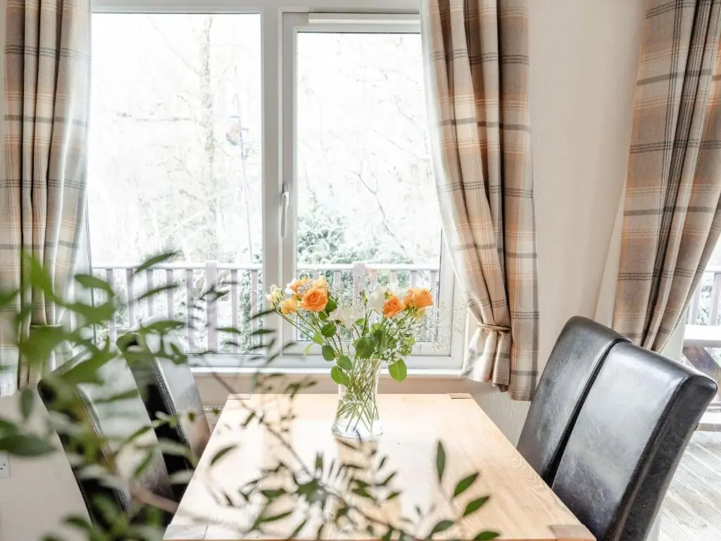 a dining room table with a vase of flowers on it at Chalet Lodge 4 by Interhome in Boat of Garten